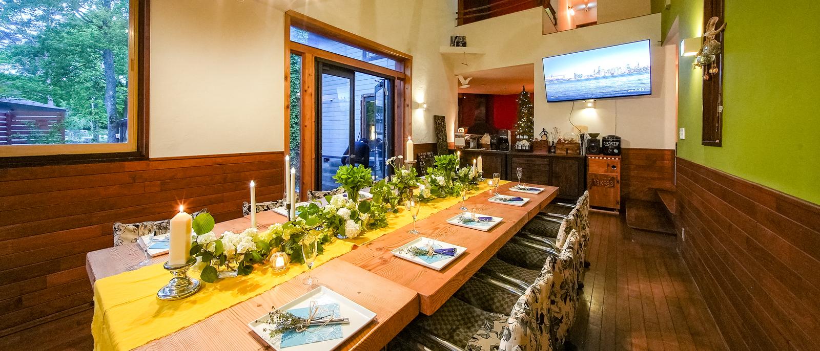 The dining table set for a group, candles and greenery down its length