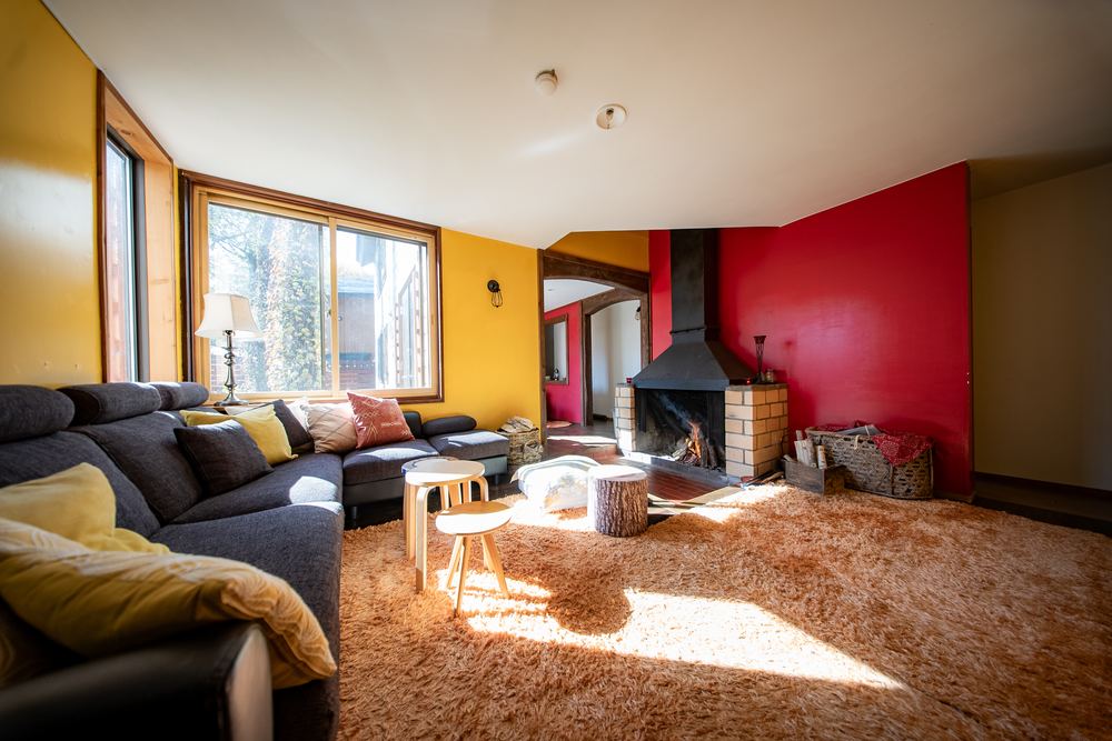 The main lounge with the wood fire lit and afternoon sun across the rug