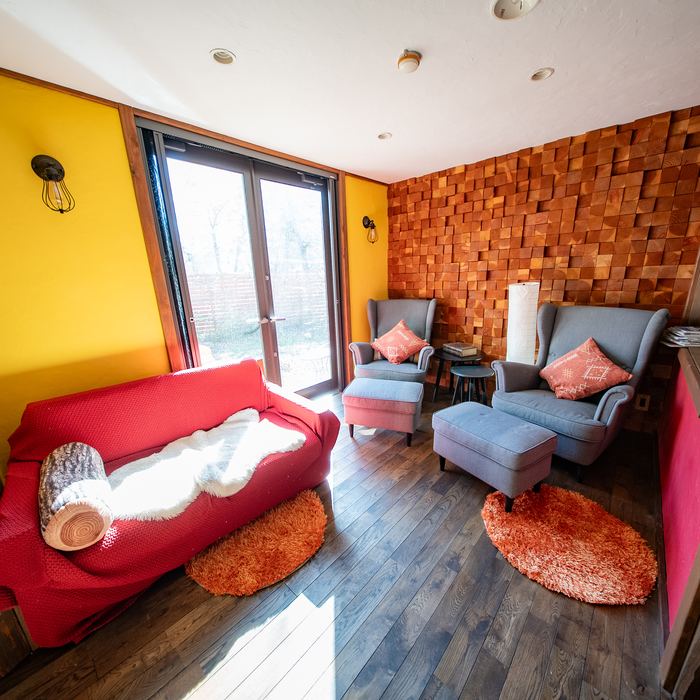 A smaller lounge with armchairs against a timber block wall